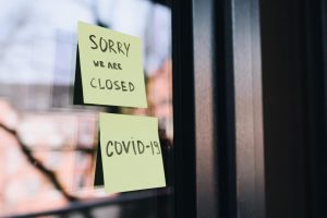Fotografia de um vidro com dois posts-its que dizem "Sorry we are closed" e "COVID-19"